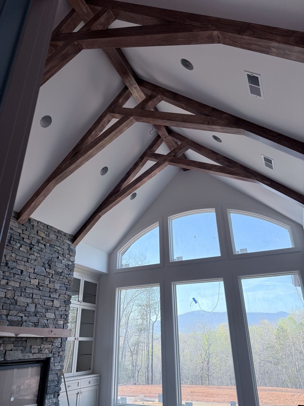 Decorative wood ceiling trusses over a stone fireplace with mountain view windows