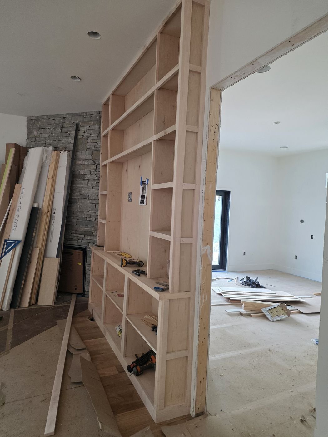 Built-in bookcase framing beside a stone fireplace