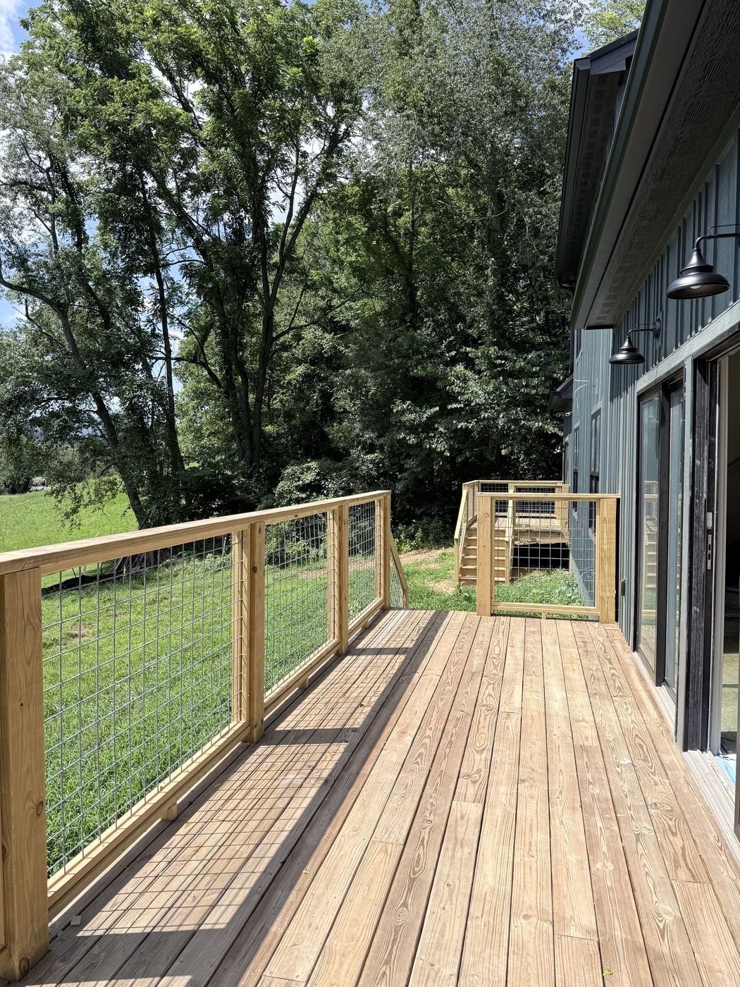 Wood deck with cable and wire railing overlooking a pasture