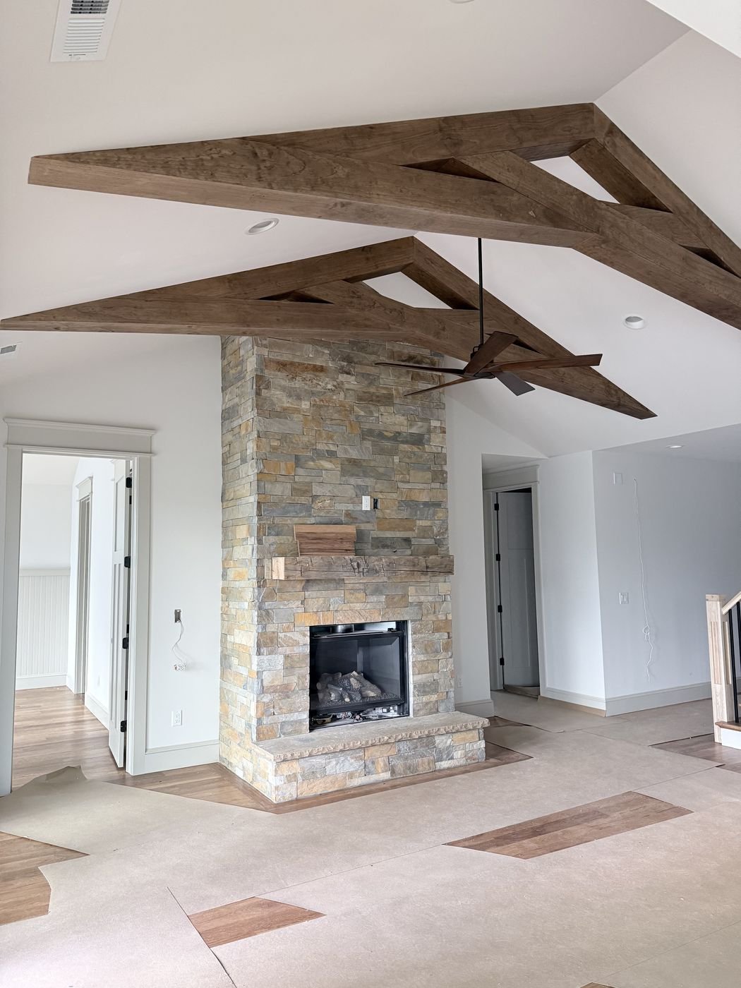 Custom wood fireplace mantel on a stone surround with decorative ceiling beams