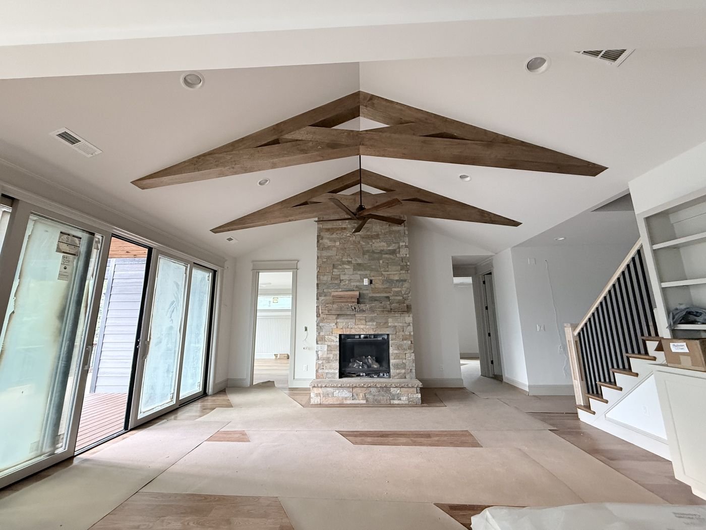 Vaulted great room with decorative wood beams, stone fireplace and stairway