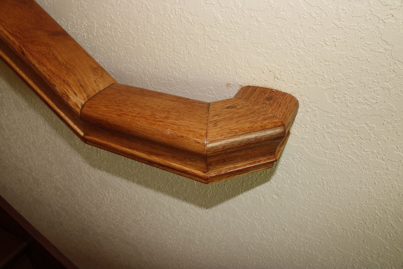 Wood stair handrail end detail, warm finish