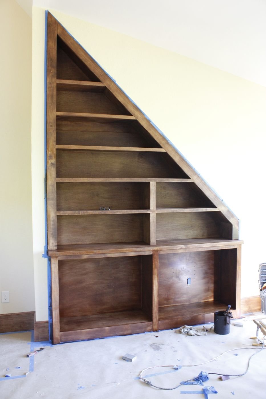 Triangular built-in bookshelf under a staircase