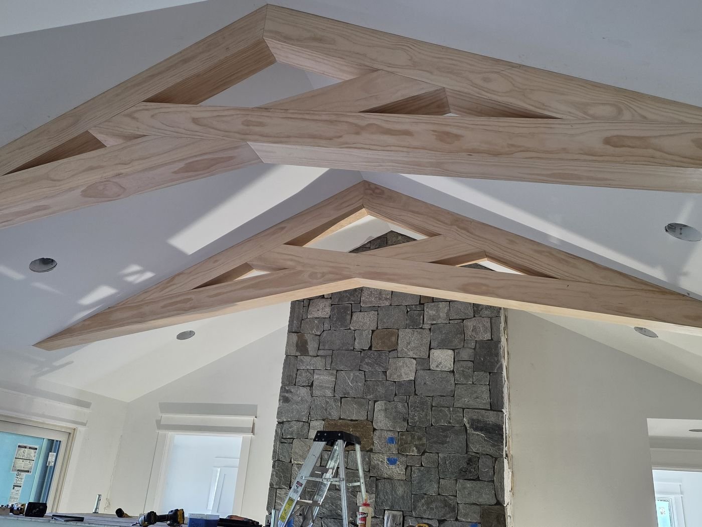 Natural wood ceiling trusses over a stone fireplace