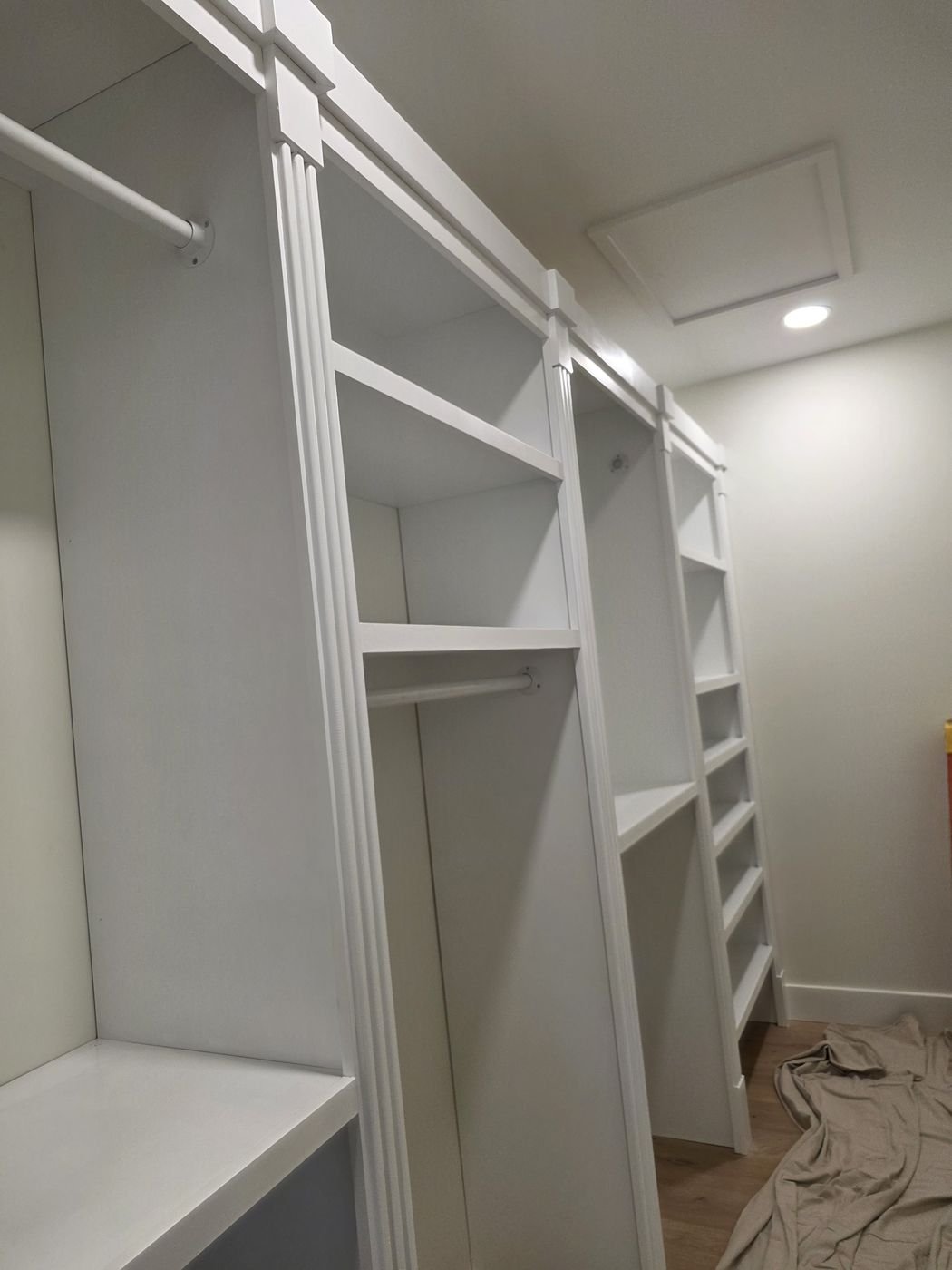Walk-in closet with custom white shelving and hanging sections
